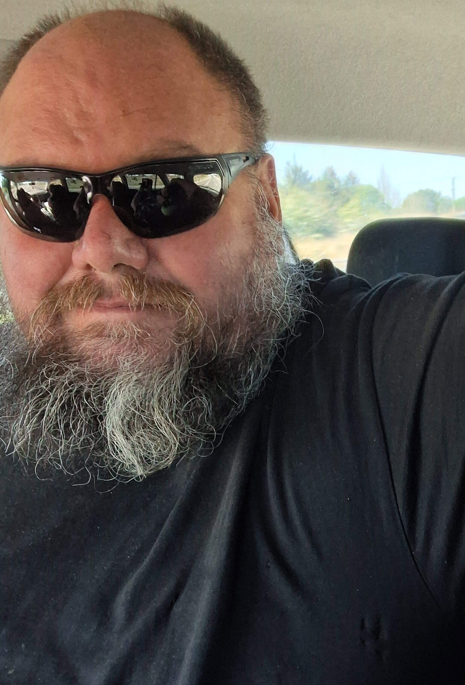 Bearded man wearing sunglasses in a car.