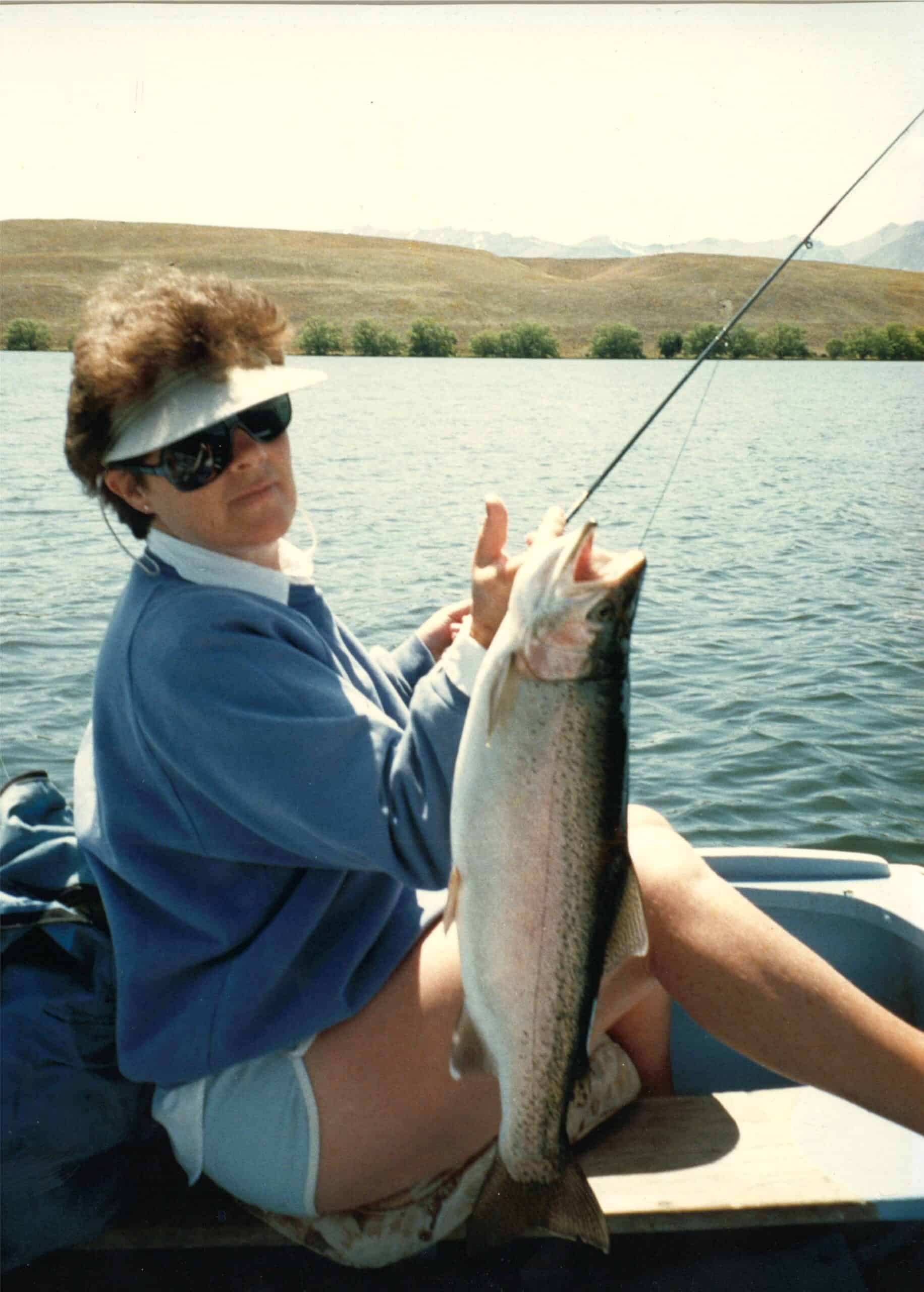 Person fishing on lake holding large trout