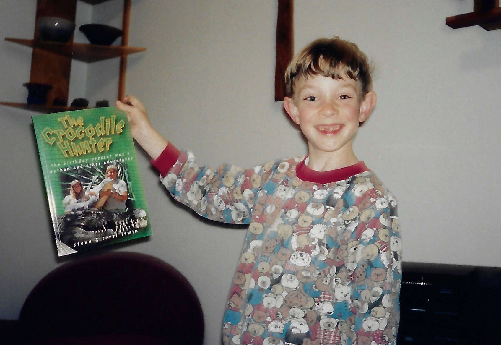 Child holding The Crocodile Hunter book, smiling.