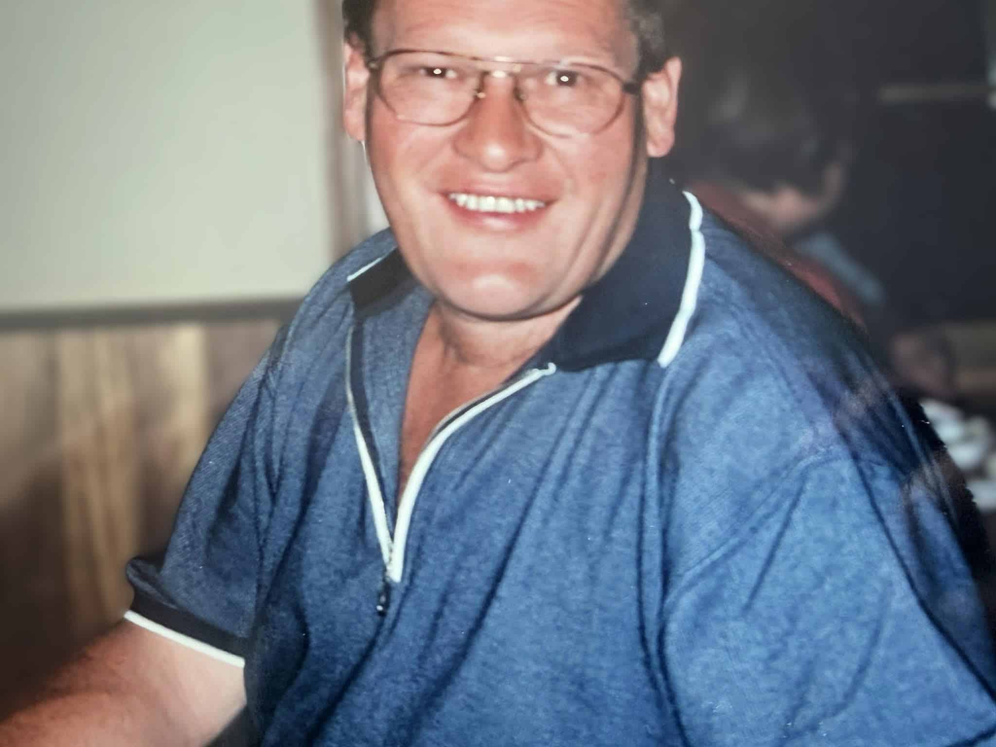 Smiling person wearing glasses and blue shirt.