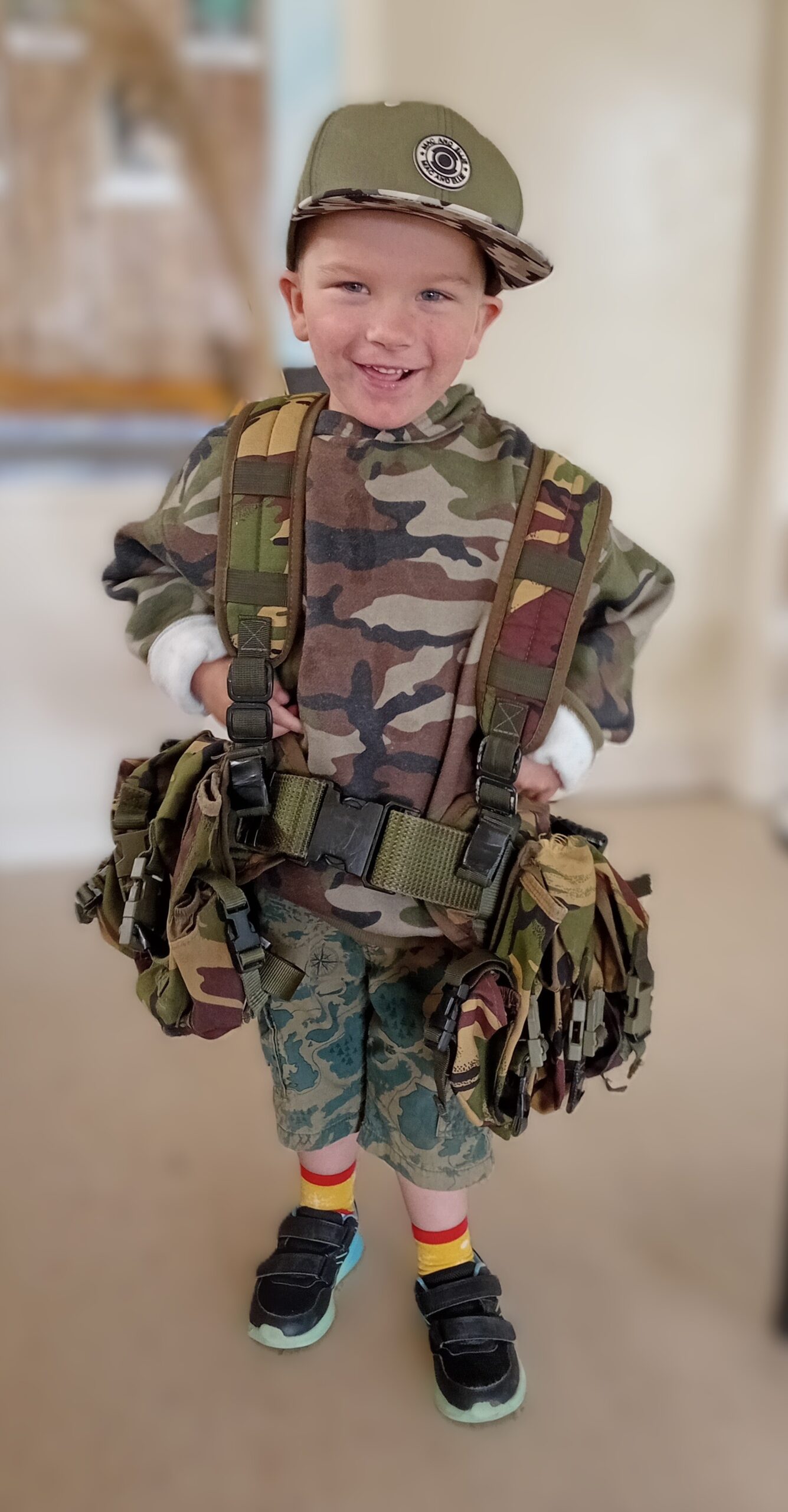 Child in camouflage gear and hat smiling